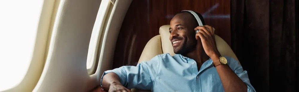 Smiling man on plane wearing noise cancelling headphones